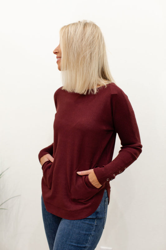 Cabernet Round Hem Sweater With Front Pockets And Sleeve Lacing Details